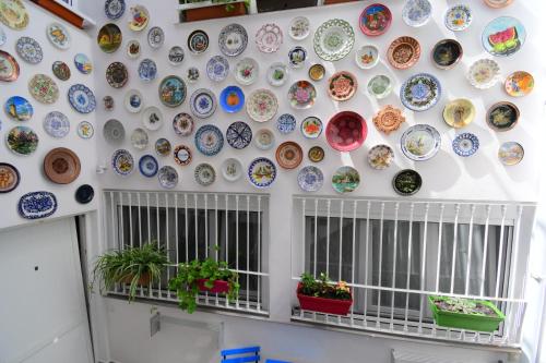 a wall of plates on a wall with potted plants at Jara Apartments ! in Málaga