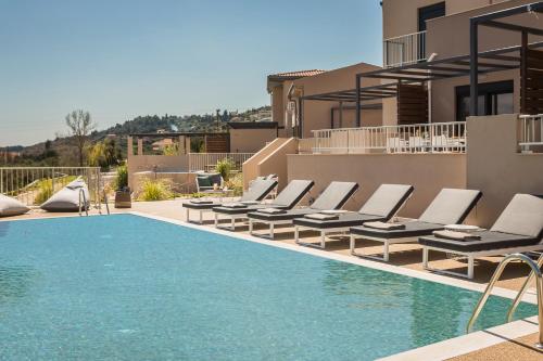 a swimming pool with lounge chairs next to a house at Ionian Village in Lixouri