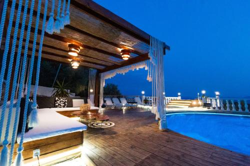 a deck with a swimming pool at night at Eva's Luxury Villa in Kritharia