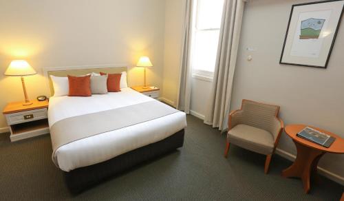 a hotel room with a large bed and a chair at Quality Hotel Mildura Grand in Mildura