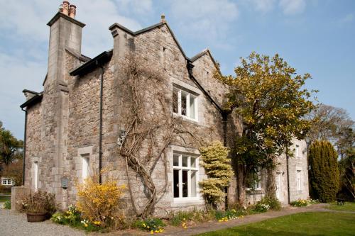 an old stone house with a chimney at Tros Yr Afon Holiday Cottages and Manor House in Beaumaris