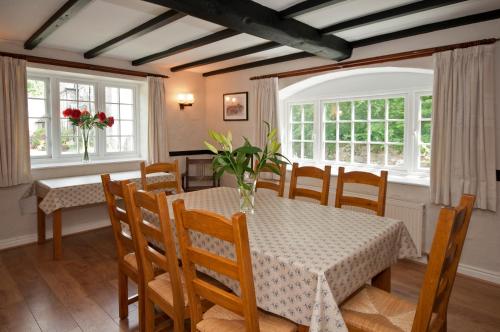 Tros Yr Afon Holiday Cottages and Manor House في بيوماريس: غرفة طعام مع طاولة وكراسي ونوافذ