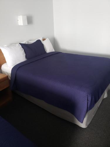 a large bed with a blue blanket and pillows at Aurora Borealis in Saint Ignace