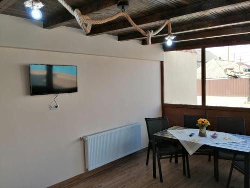 ein Esszimmer mit einem Tisch und einem TV an der Wand in der Unterkunft Pensiunea Corina Tulcea in Tulcea