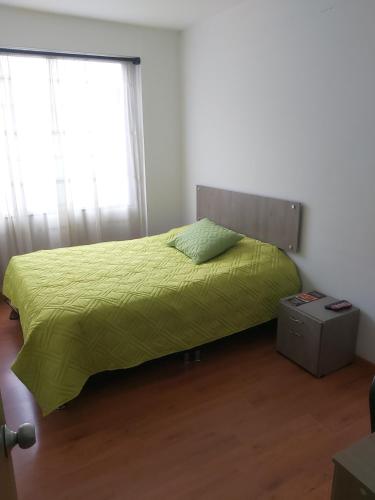 a bedroom with a bed with a green comforter at Hospedaje Sary House in Bogotá