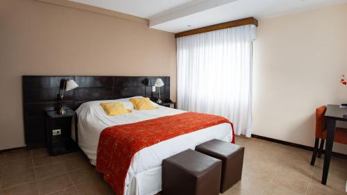 a bedroom with a large bed with a red blanket at Hotel Poincenot in El Chalten
