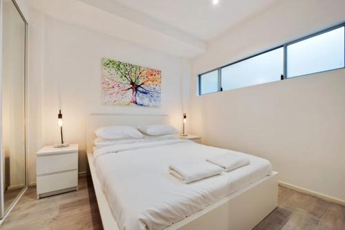 a white bedroom with a bed and a painting on the wall at Swainson on Bent in Adelaide