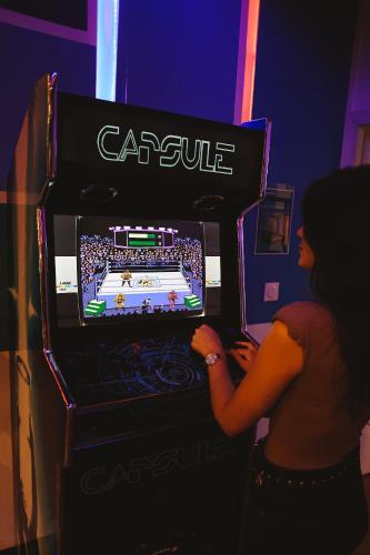 a woman playing a video game in a game machine at Capsule Gaming balnéo & billard & babyfoot & sauna 2 chambres in Valenciennes