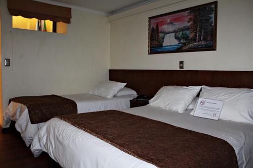 two beds in a hotel room with a sign on them at Hotel Newen in Temuco
