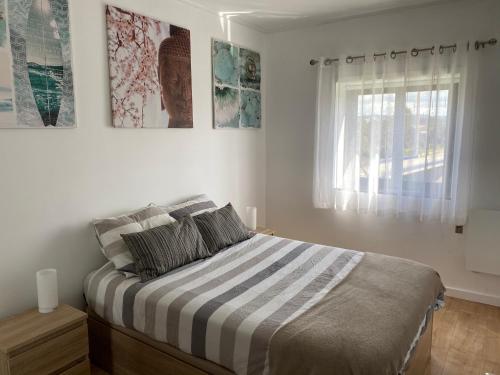 a bedroom with a bed with a striped blanket and a window at Appartement à Esmoriz de 3 pièces - 72m2 in Esmoriz