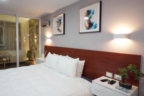 - une chambre avec un grand lit blanc et deux photos sur le mur dans l'établissement Hotel Don Bartolo, à Espinar