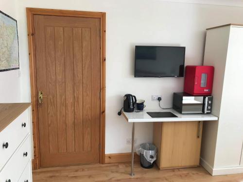 Habitación con escritorio, TV y puerta. en Croft No.8 Bed & Breakfast, en Ullapool