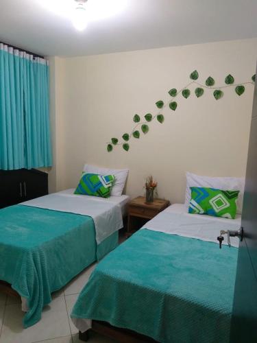 two beds in a room with green plants on the wall at Hermoso Apartamento en San Gil in San Gil