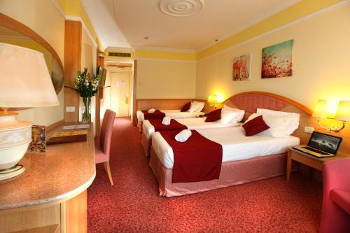 a hotel room with three beds and a desk at Villa Fiorita in Monastier di Treviso