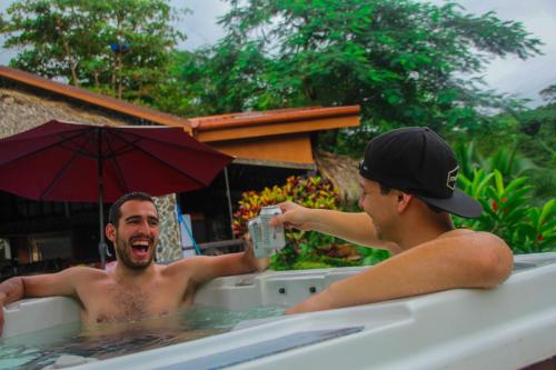 two men laughing in a bath tub with an umbrella at Hotel Poza Blanca Lodge in San Mateo