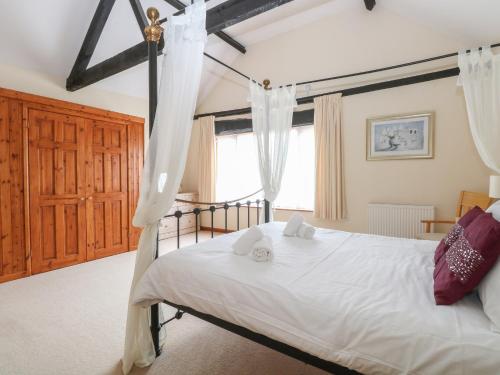 1 dormitorio con 1 cama con sábanas y cortinas blancas en Beechwood, en Wood Norton
