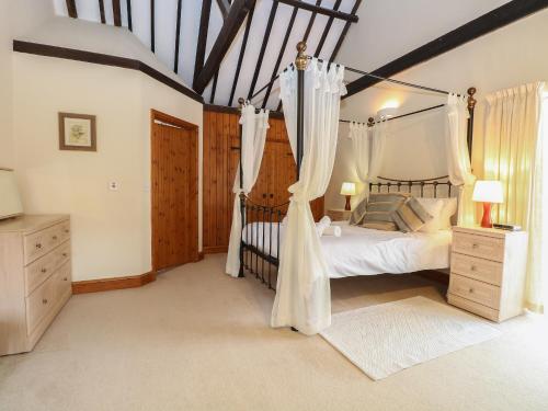 a bedroom with a canopy bed with curtains in it at Pear Tree in Wood Norton