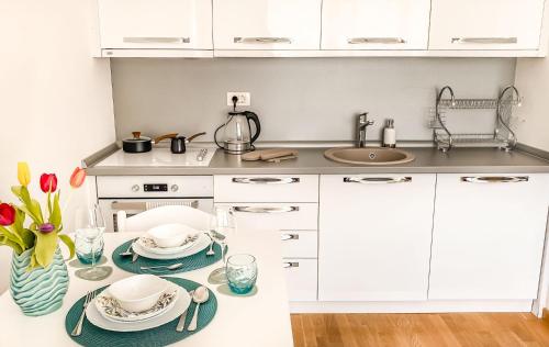 a kitchen with white cabinets and a table with dishes at Four Views Apartments in Budva