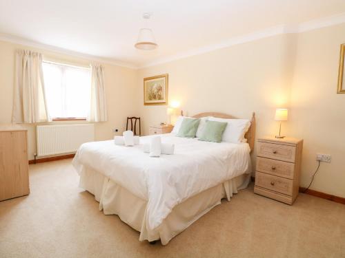 a bedroom with a large white bed and a window at Sycamore in Wood Norton