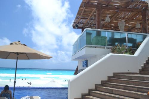 a woman sitting under an umbrella next to the beach at Ocean View Condo in Cancún