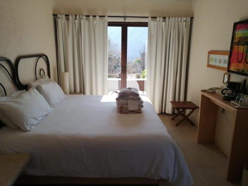 Un dormitorio con una gran cama blanca y una ventana en Hostal de la Luz - Spa Holistic Resort en Tepoztlán