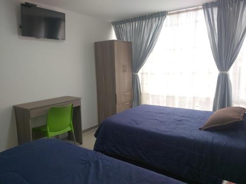 1 dormitorio con 2 camas, escritorio y ventana en Hospedaje Sary House, en Bogotá