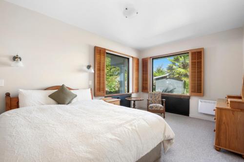 een slaapkamer met een wit bed en een raam bij Lakefront Villa - Waitahanui Holiday Home in Waitahanui