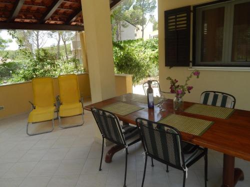 een patio met een houten tafel en gele stoelen bij Apartment Deni - 70m from beach in Milna