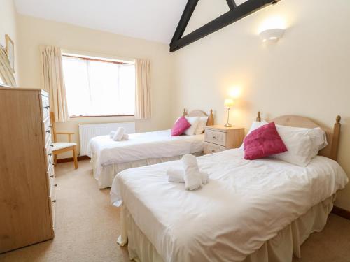 a bedroom with two beds with pink and white pillows at Holly Berry in Wood Norton