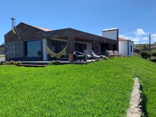 ein Haus mit Rasen davor in der Unterkunft Villa Mariense in Vila do Porto