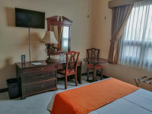 1 dormitorio con escritorio, mesa y cama en Hotel Royal Palace, en Guatemala