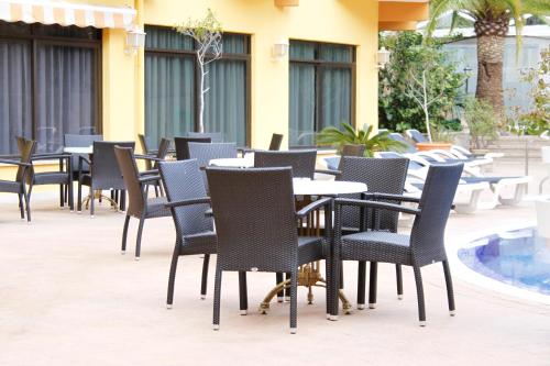 a row of tables and chairs with a dog sitting at them at Hotel Morlans in Paguera