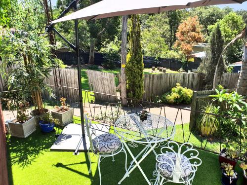 a garden with a table and chairs and an umbrella at UNIQUE 1920's Historic Retreat! Pet Friendly! in Springwood