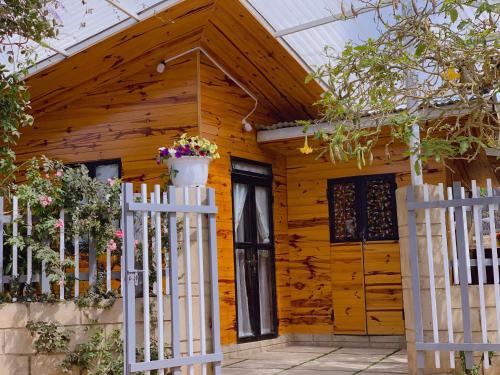 a wooden house with a white picket fence at EUDORA HOUSE 2 in Da Thien