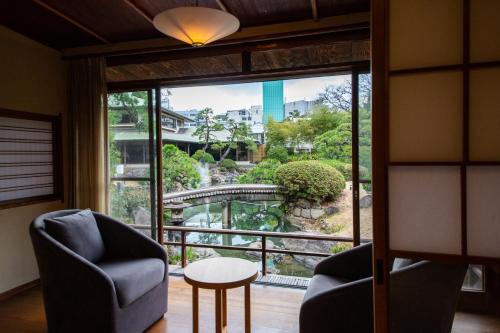 a room with a large window with a chair and a table at Suisui Garden Ryokan (in the Art Hotel Kokura New Tagawa) in Kitakyushu