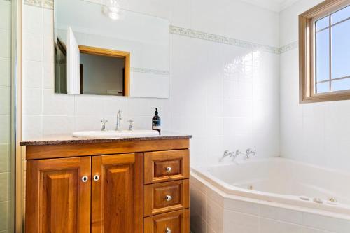 a bathroom with a sink and a tub and a mirror at Cottages on Lovedale - Cottage No. 2 in Lovedale