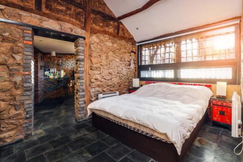 a bedroom with a large bed in a stone wall at Sansa Village Boutique Hotel at Mutianyu Great Wall in Huairou