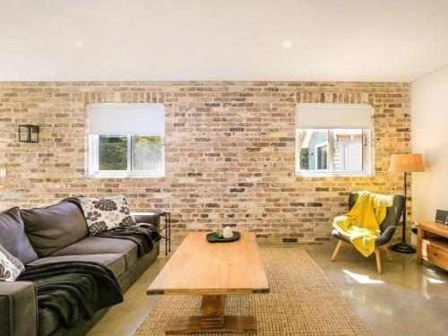 a living room with a couch and a brick wall at Amaroo in Bowral