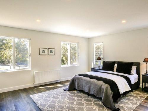 a bedroom with a bed and two windows at Amaroo in Bowral