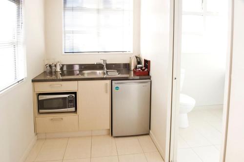 a small kitchen with a sink and a refrigerator at Dunedin Palms Motel in Dunedin