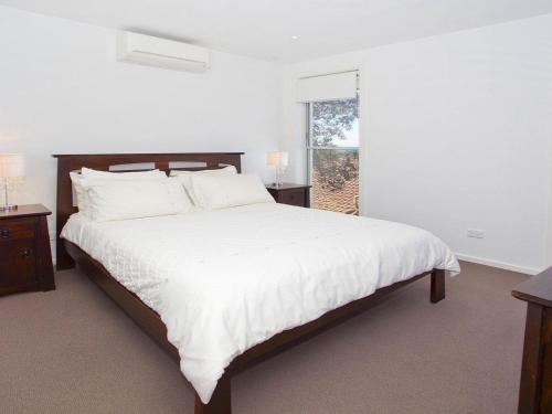 a white bedroom with a large bed and a window at Aqua in Kiama Downs