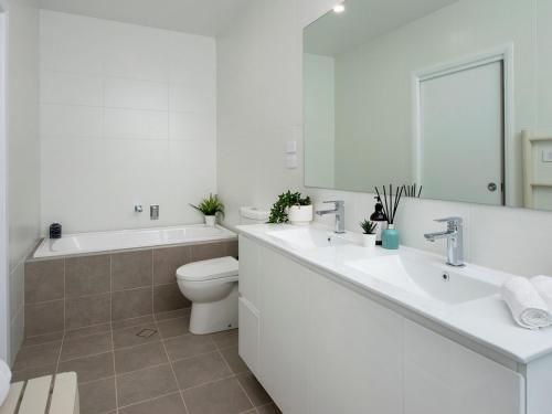 een badkamer met een wastafel, een toilet en een bad bij Blue Pelican in Kiama Downs