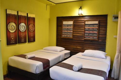 three beds in a room with yellow walls at Baanfai Guesthouse Chiangkhong in Chiang Khong