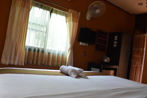 a towel laying on a bed in front of a window at Baanfai Guesthouse Chiangkhong in Chiang Khong