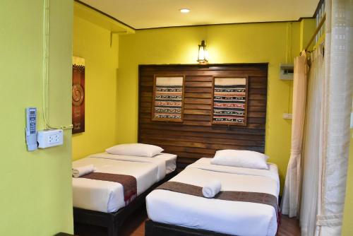 two beds in a room with yellow walls at Baanfai Guesthouse Chiangkhong in Chiang Khong