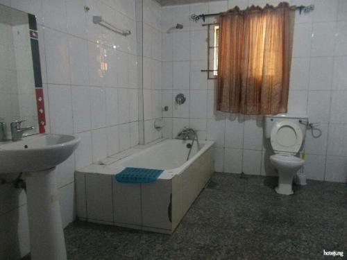 a bathroom with a tub and a toilet and a sink at Room in Lodge - Cynergy Suites Festac Town in Amuwo