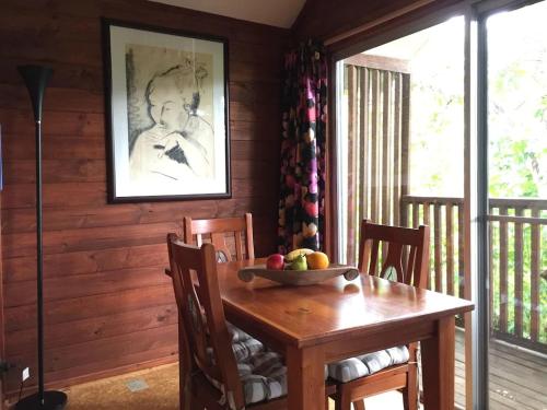 a wooden dining room table with a bowl of fruit on it at Potters Cottage in Bellingen
