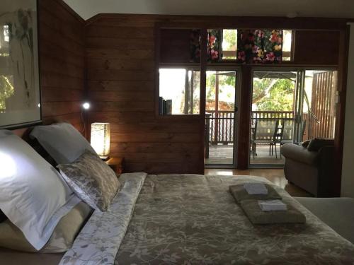 ein Schlafzimmer mit einem Bett in einem Zimmer mit Fenstern in der Unterkunft Potters Cottage in Bellingen