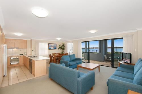 a living room with two blue couches and a kitchen at Sandcastles On The Broadwater in Gold Coast