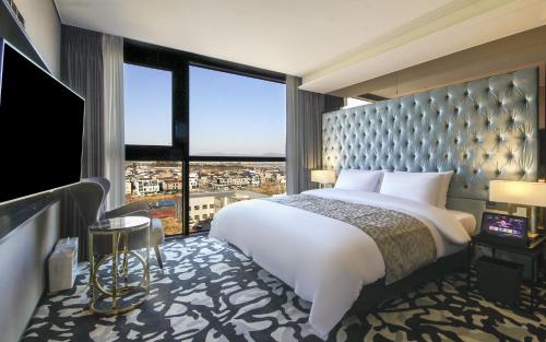 a bedroom with a large bed and a large window at Best Louis Hamilton Hotel West Busan in Busan
